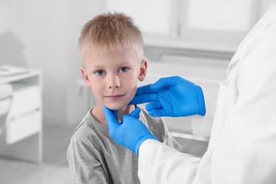 Photo of Endocrinologist examining boy's thyroid gland at hospital, closeup