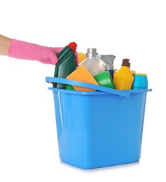 Photo of Woman taking bottle of detergent from bucket with cleaning supplies on white background