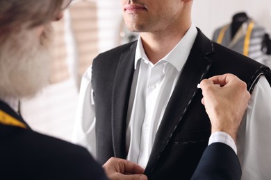 Professional tailor working with client in atelier, closeup