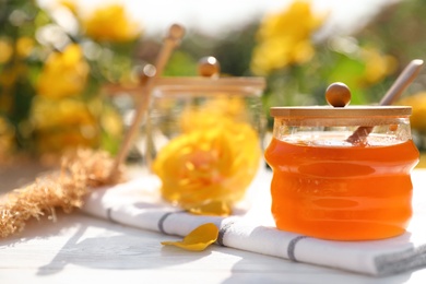 Jar with fresh rose honey on white wooden table outdoors. Space for text