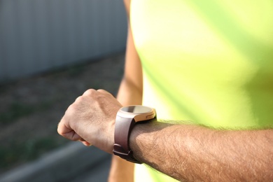 Photo of Man checking fitness tracker after training outdoors, closeup
