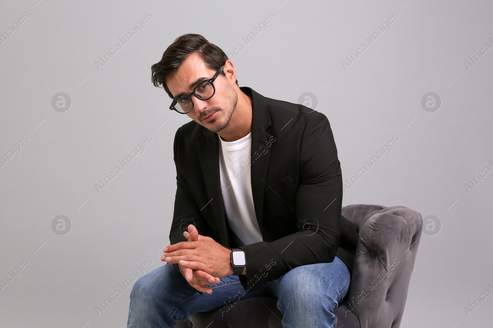 Photo of Handsome young businessman sitting in armchair on grey background