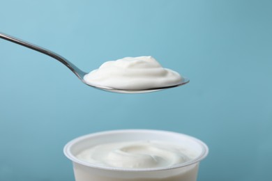 Photo of Eating delicious natural yogurt on light blue background