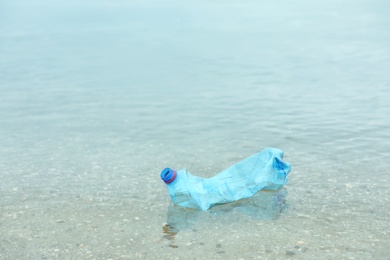 Photo of Used plastic bottle floating on water surface, space for text. Recycling problem