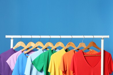 Photo of Bright clothes on blue background, space for text. Rainbow colors