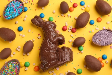 Photo of Flat lay composition with chocolate Easter bunny, eggs and candies on yellow background