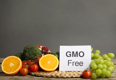 Tasty fresh GMO free products and paper card on wooden table against grey background