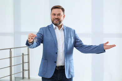 Male real estate agent holding key in new apartment