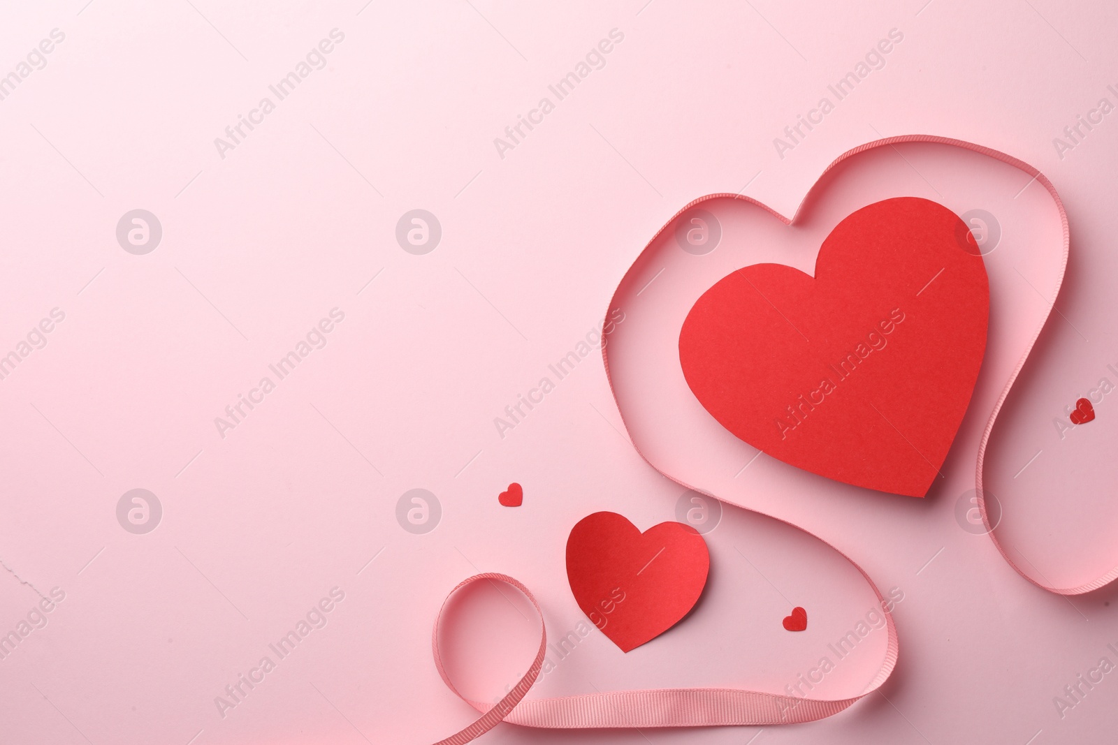 Photo of Paper hearts and ribbon on pink background, flat lay. Space for text