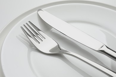 Clean plates, fork and knife on white background, closeup