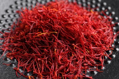 Photo of Aromatic dried saffron on black plate, closeup