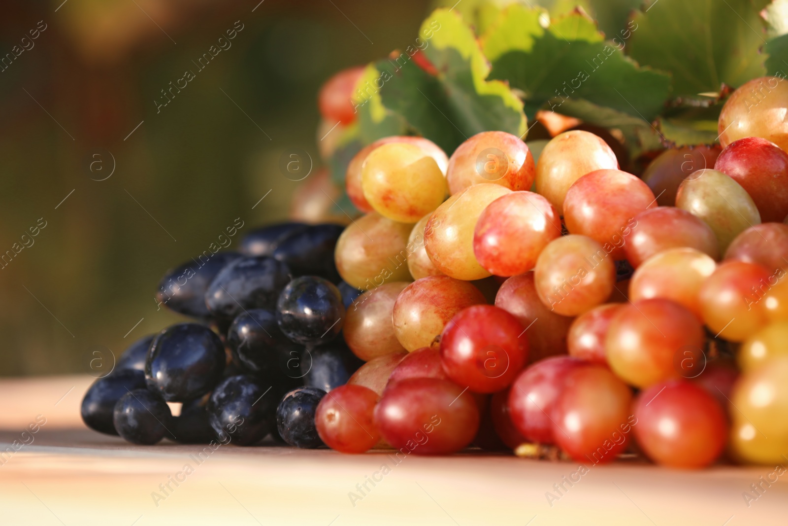 Photo of Fresh ripe juicy grapes on table against blurred background