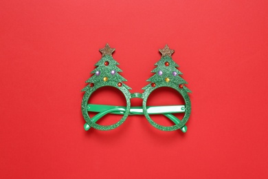 Funny glasses in shape of Christmas tree on red background, top view