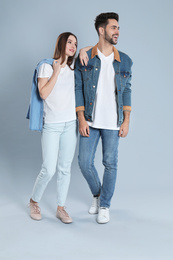 Photo of Young couple in stylish jeans on grey background