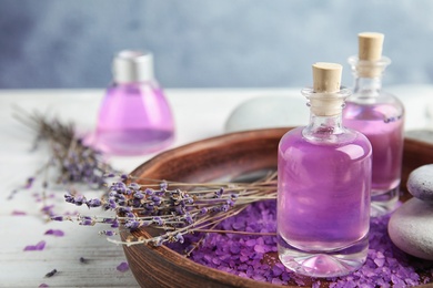 Photo of Bottles with natural herbal oil and lavender flowers on wooden table
