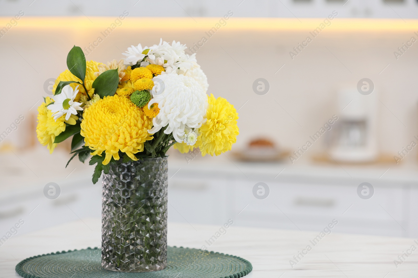 Photo of Bouquet of beautiful chrysanthemum flowers on table in kitchen, space for text