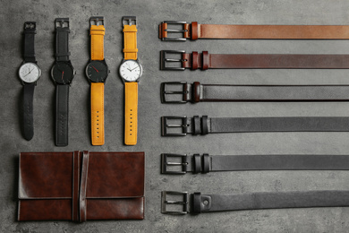Photo of Leather wallet, belts and wristwatches on grey stone table, flat lay