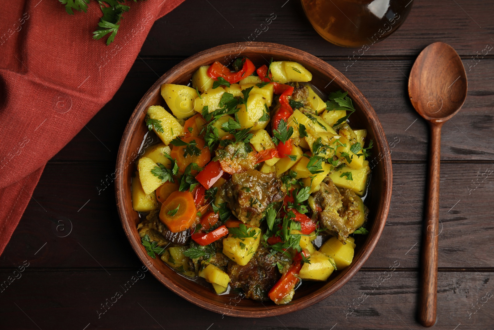 Photo of Tasty cooked dish with potatoes in earthenware served on wooden table, flat lay