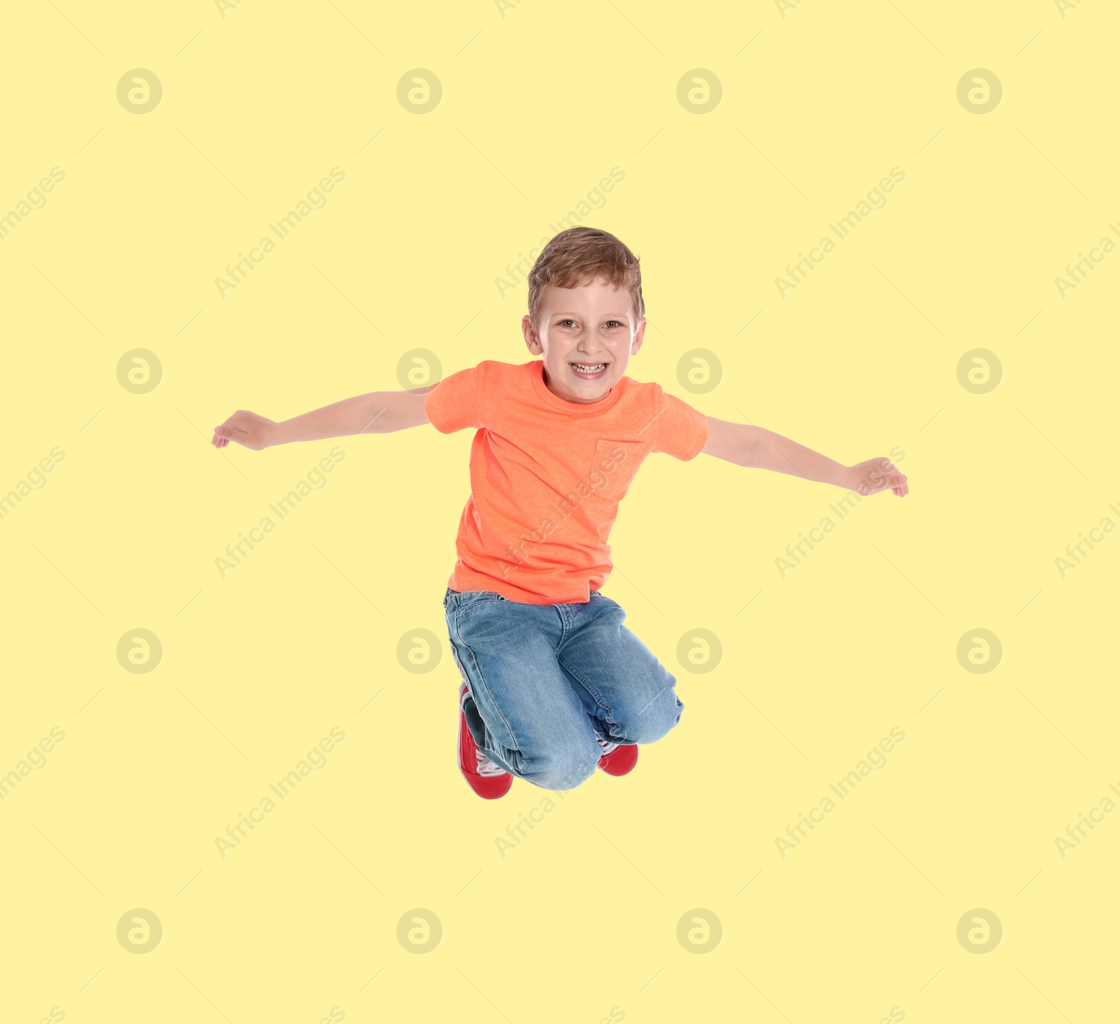 Image of Happy boy jumping on beige background, full length portrait