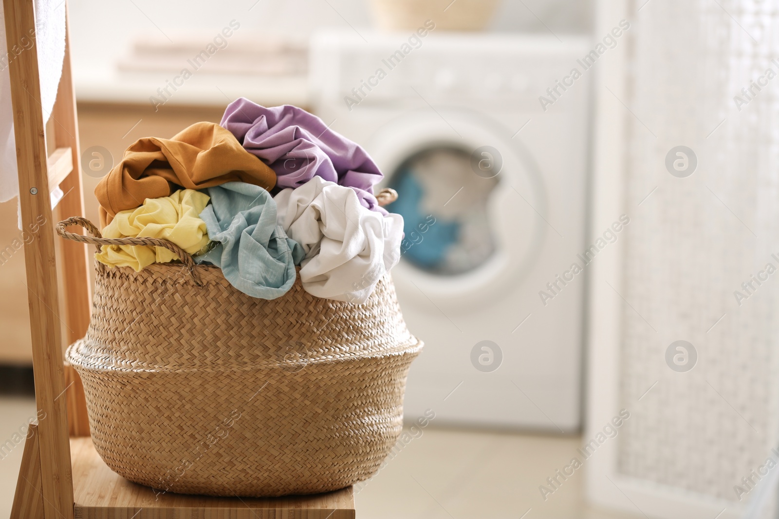 Photo of Wicker basket with dirty clothes on chair in bathroom. Space for text