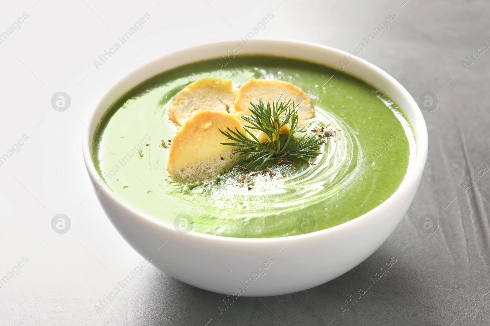 Photo of Fresh vegetable detox soup with croutons in dish on table