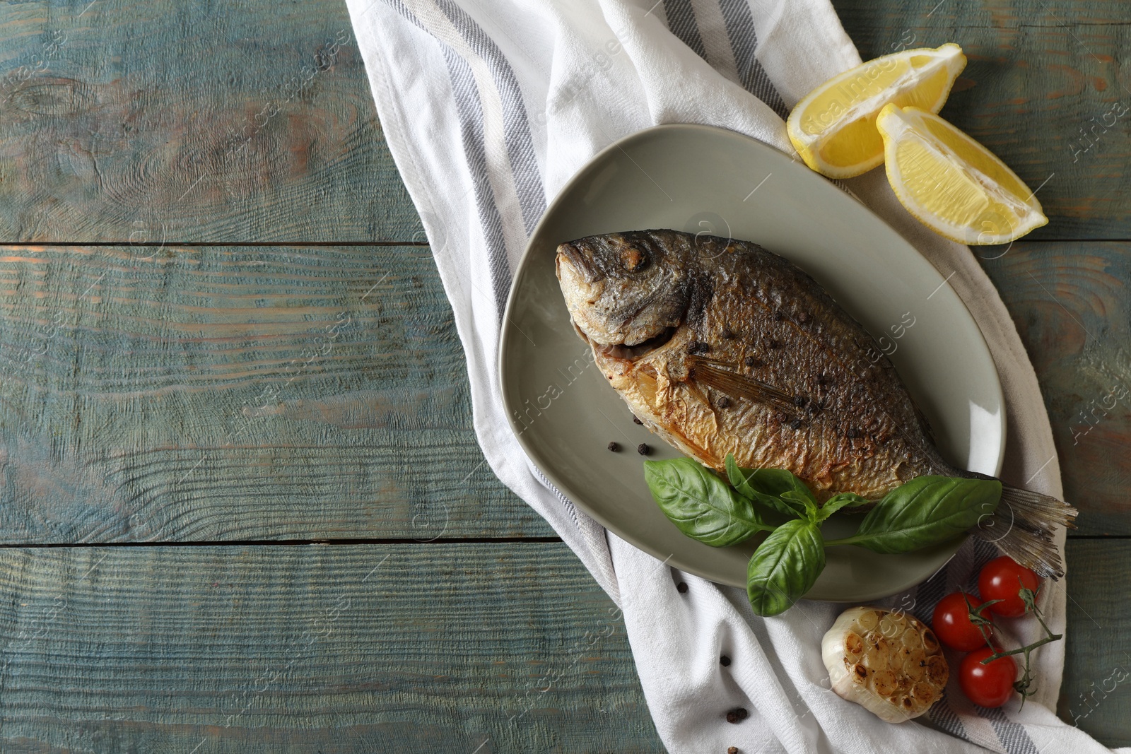 Photo of Delicious dorado fish with basil and spices served on wooden table, flat lay. Space for text