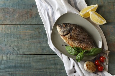 Delicious dorado fish with basil and spices served on wooden table, flat lay. Space for text