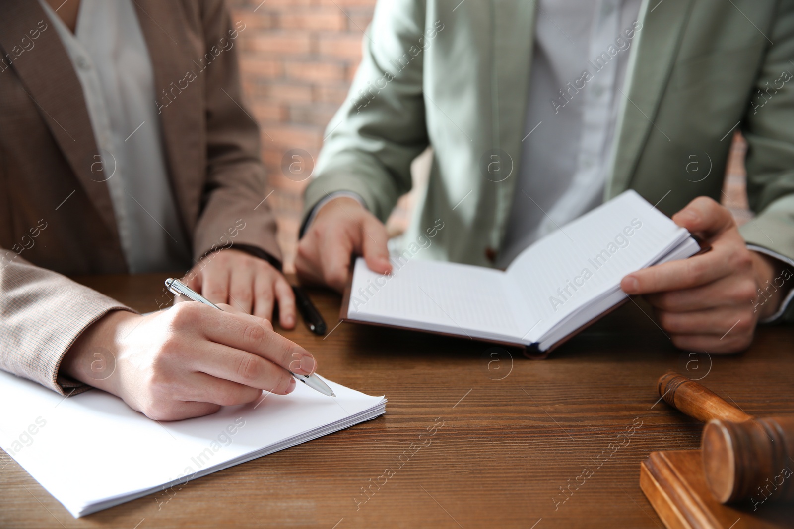 Photo of Notary and client working with papers at table in office, closeup. Law and justice concept