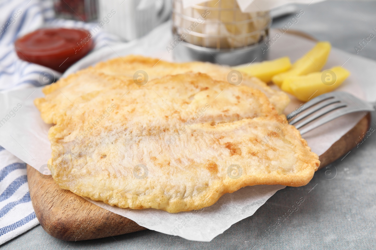 Photo of Delicious fish and chips served on gray table, closeup