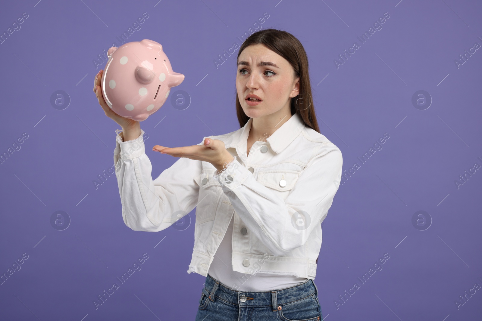 Photo of Sad woman with piggy bank on purple background