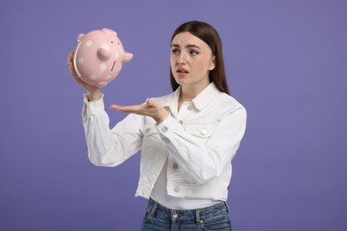 Photo of Sad woman with piggy bank on purple background