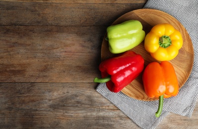 Board with ripe bell peppers on wooden table, top view. Space for text