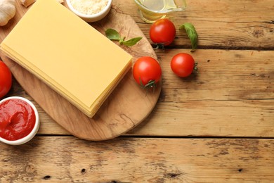 Photo of Flat lay composition with products for cooking lasagna on wooden table. Space for text