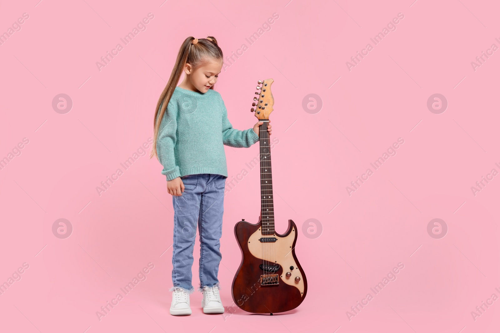 Photo of Happy girl with electric guitar on pink background