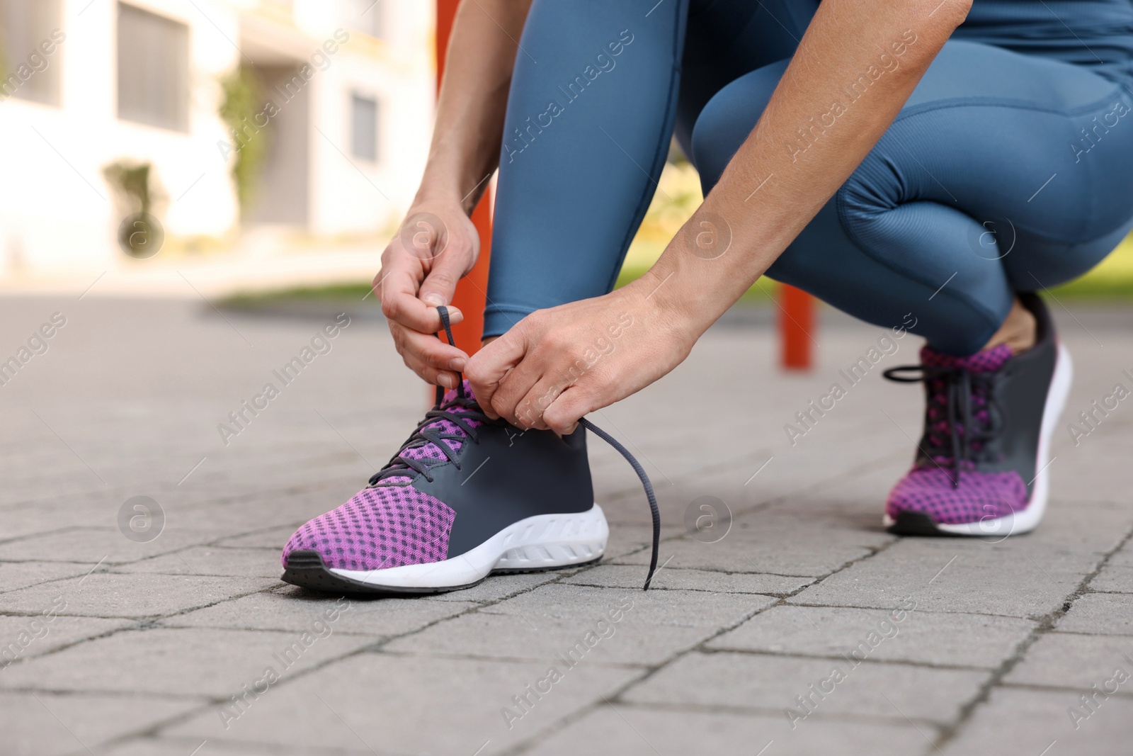 Photo of Woman tying shoelaces before training outdoors, closeup. Space for text