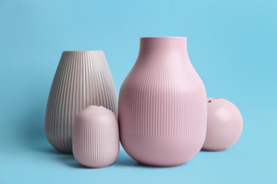 Stylish empty ceramic vases on light blue background