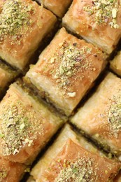 Photo of Delicious fresh baklava with chopped nuts as background, top view. Eastern sweets