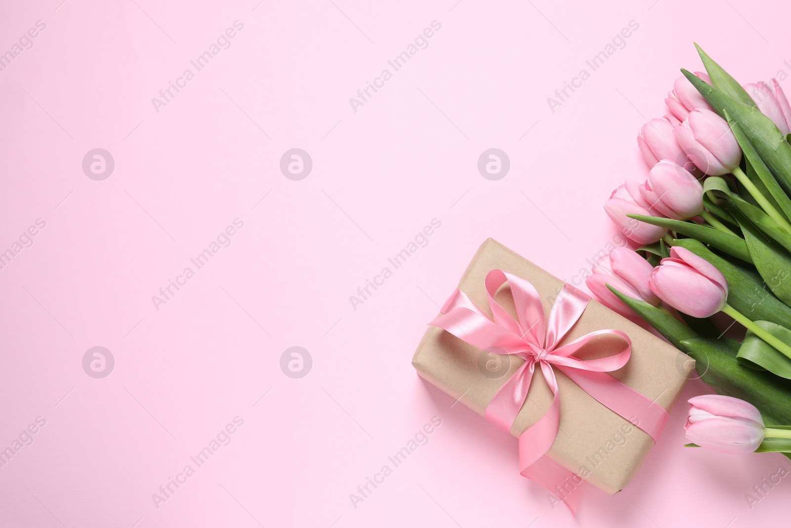 Photo of Beautiful gift box and bouquet of tulip flowers on pink background, flat lay. Space for text
