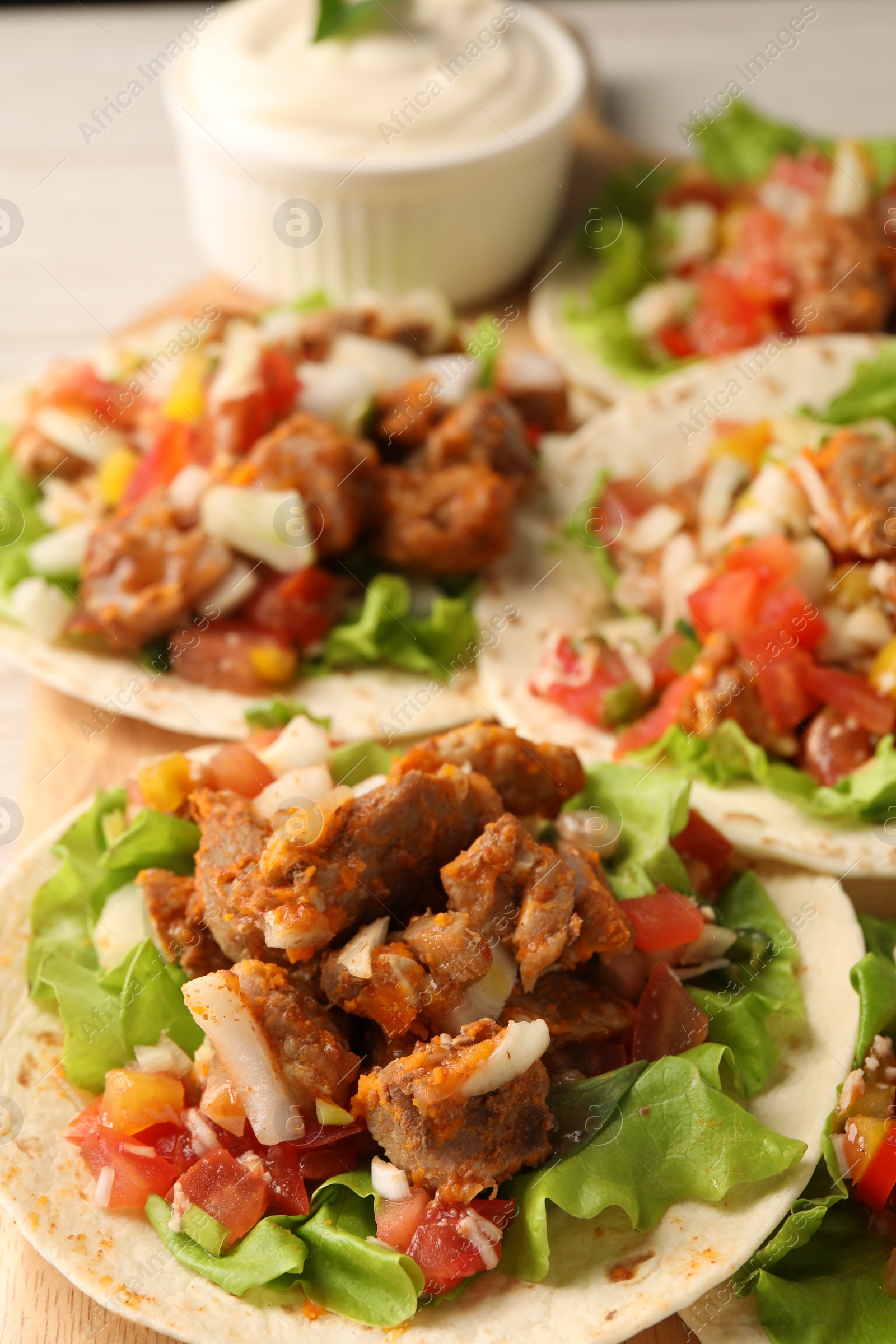 Photo of Delicious tacos with vegetables and meat on table, closeup