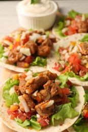 Photo of Delicious tacos with vegetables and meat on table, closeup