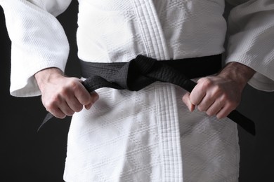 Photo of Karate coach wearing kimono and black belt on dark background, closeup