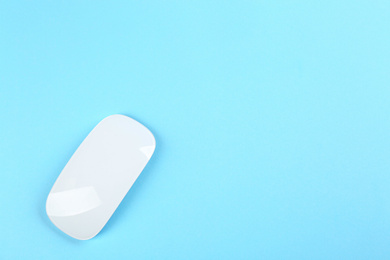 Modern wireless optical mouse on light blue background, top view. Space for text