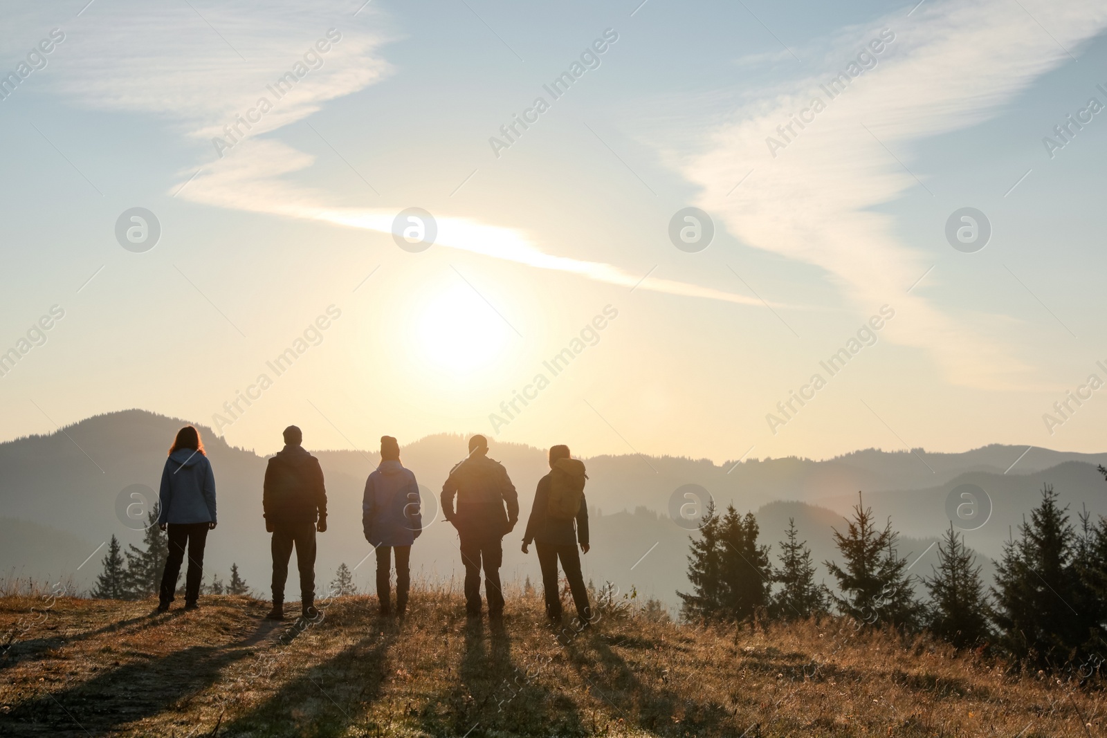 Photo of Group of people enjoying sunrise in mountains, back view. Space for text