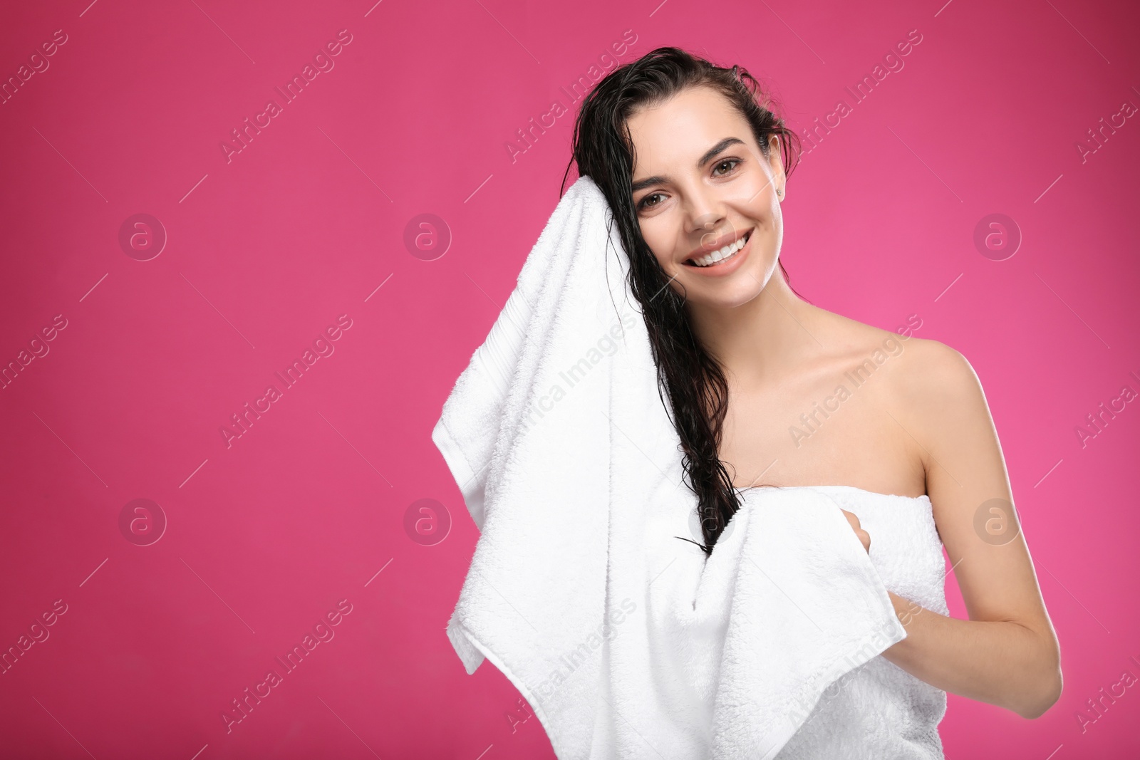 Photo of Happy young woman drying hair with towel after washing on pink background. Space for text