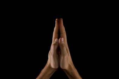 Photo of Man praying against black background, closeup view