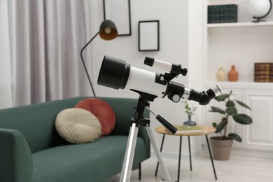 Photo of Tripod with modern telescope in living room