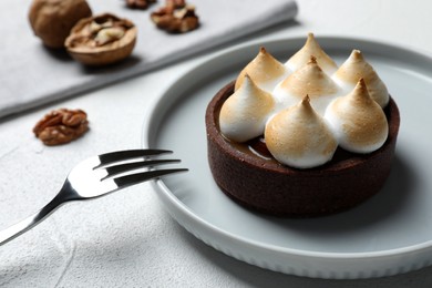 Photo of Delicious salted caramel chocolate tart with meringue served on light table, closeup