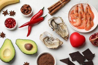 Photo of Natural aphrodisiac. Different food products and red decorative heart on white table, flat lay