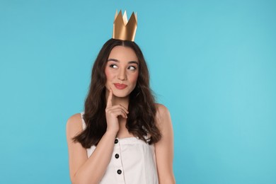 Beautiful young woman with princess crown on light blue background