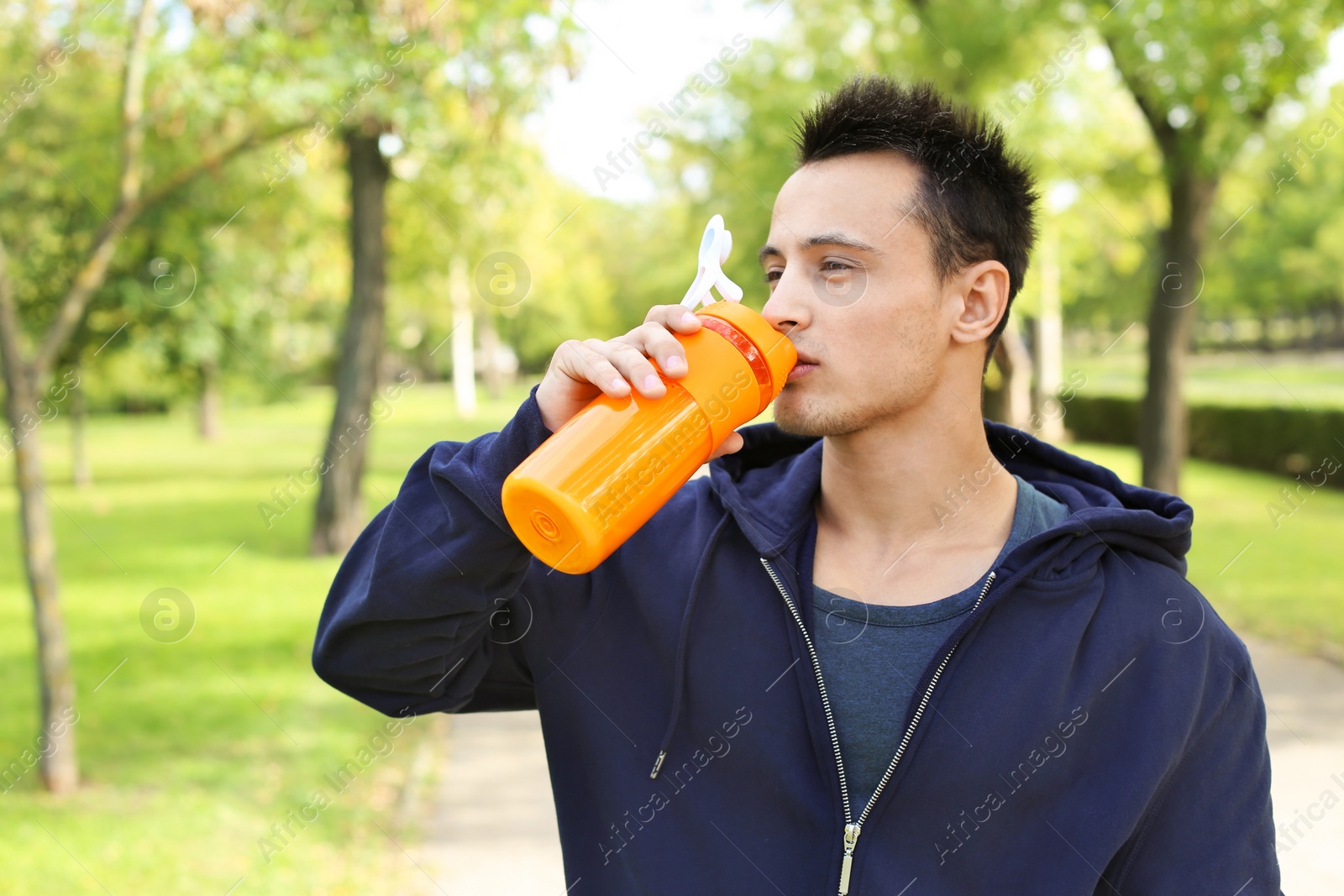 Photo of Young man drinking protein shake in green park